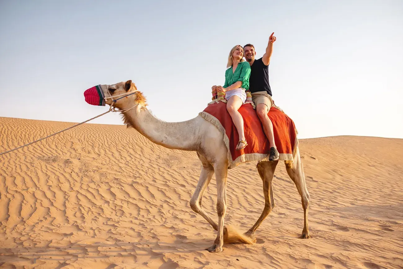 Couple enjoying a camel ride on the dunes