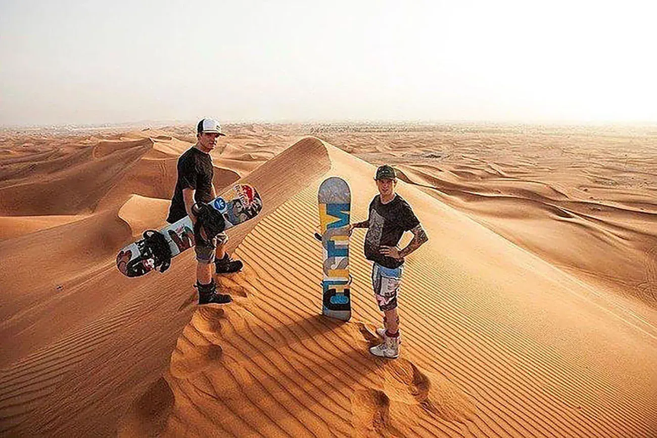 Friends with sandboards in the red dunes
