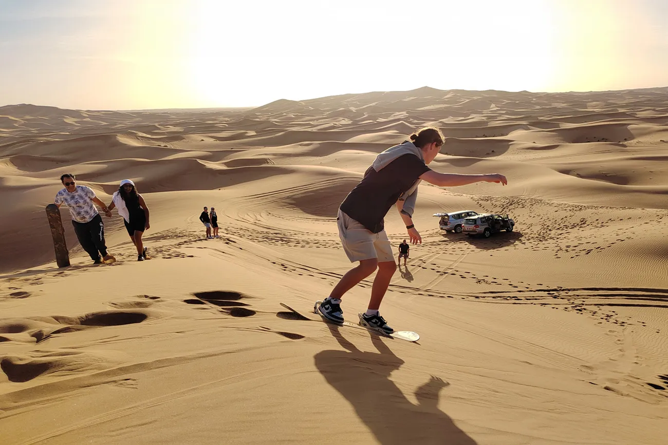 Sandboarding down a desert dune